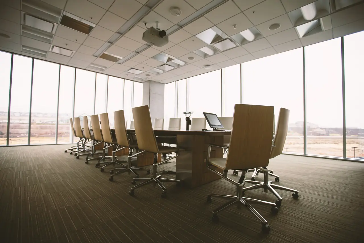 Empty boardroom with a long conference table and city view