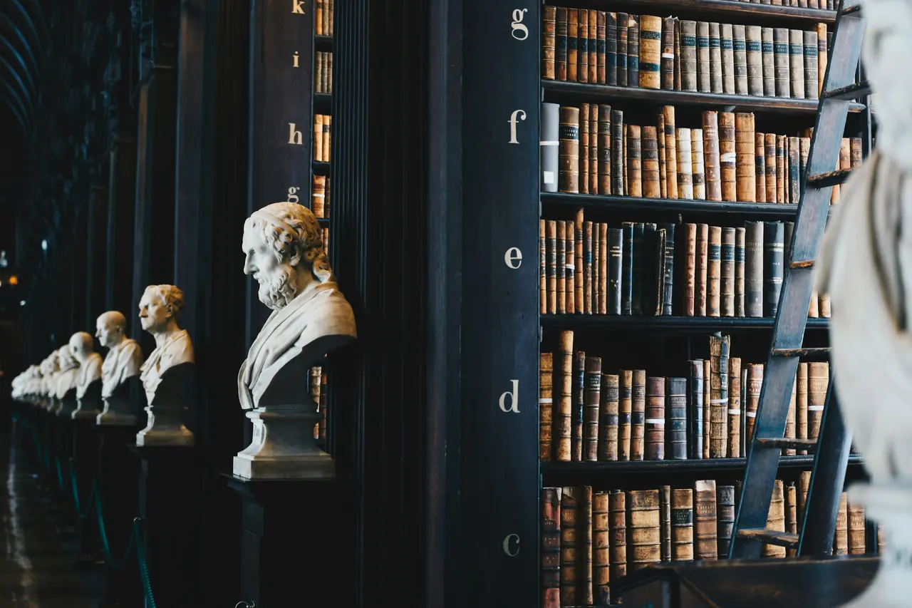 Library shelves of old books with marble busts